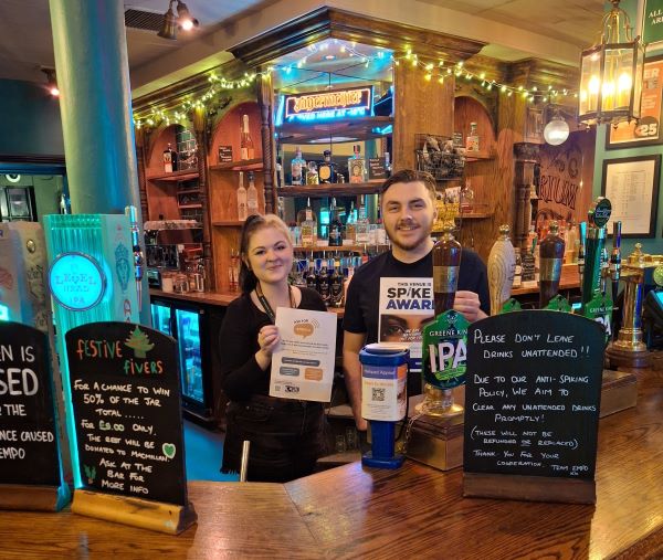 Staff behind the bar at a venue with safety information