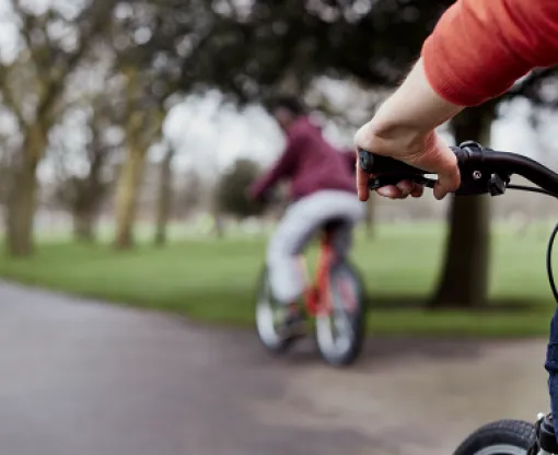 Two people on bikes cycling through a park