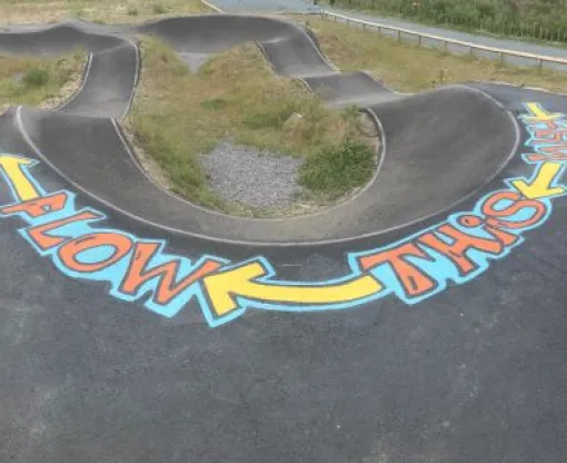 Undulating tarmaced cycle paths with Flow this way written at the bottom