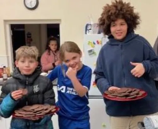 Three children in a line with two of them holding a plate of cookies