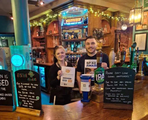 Staff behind the bar at a venue with safety information