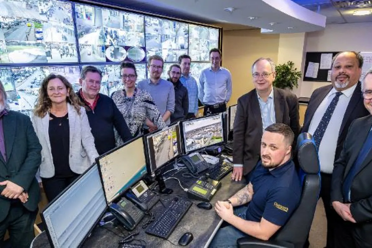 Bank of CCTV screens with group pf councillors and officers