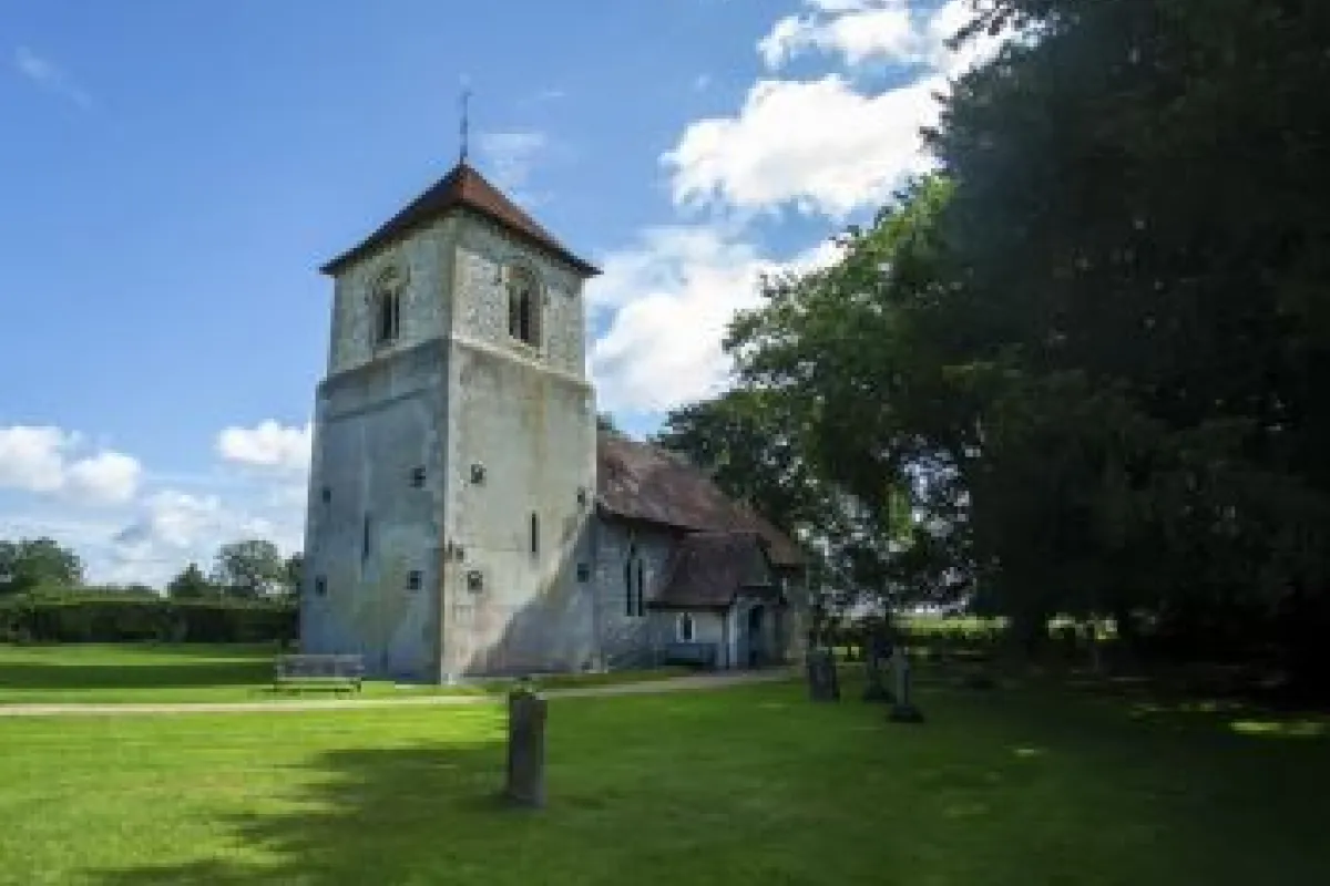 Church in Winchfield with blue sky behind surrounded by green grass and the churchyard