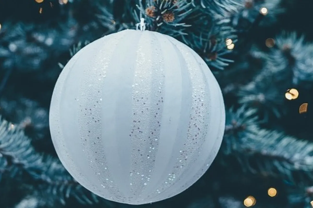 White and blue Christmas baubles on a tree with fairy lights