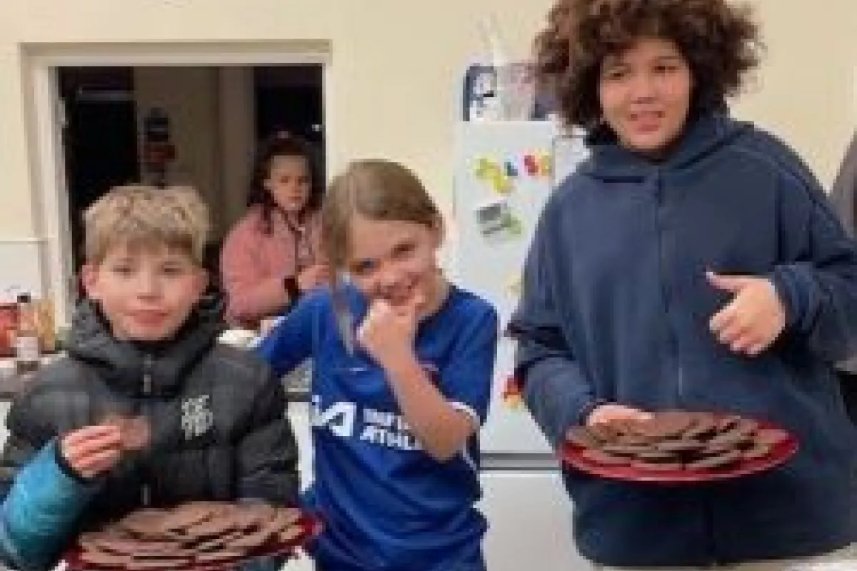 Three children in a line with two of them holding a plate of cookies