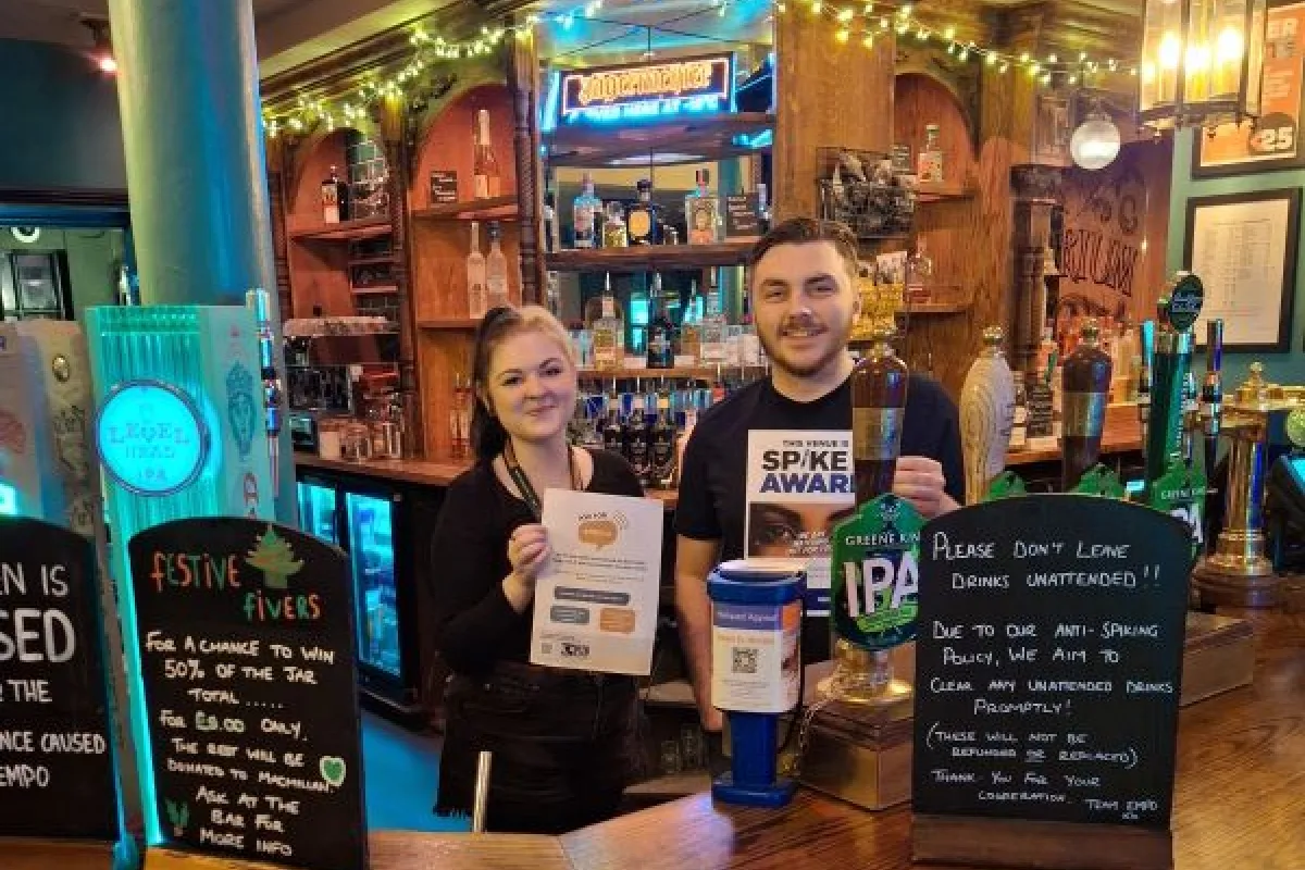 Staff behind the bar at a venue with safety information