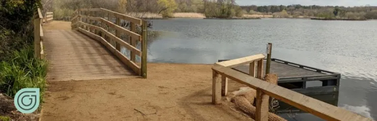 View of a lake with walkway in foreground and trees and bushes