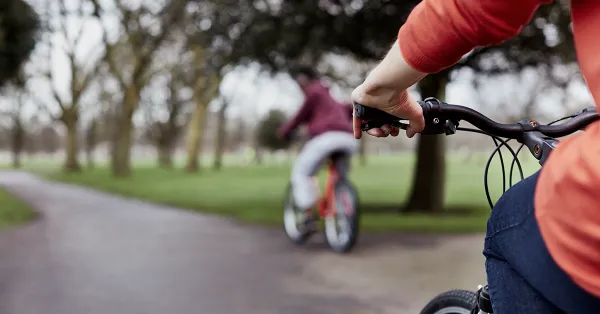 Two people on bikes cycling through a park