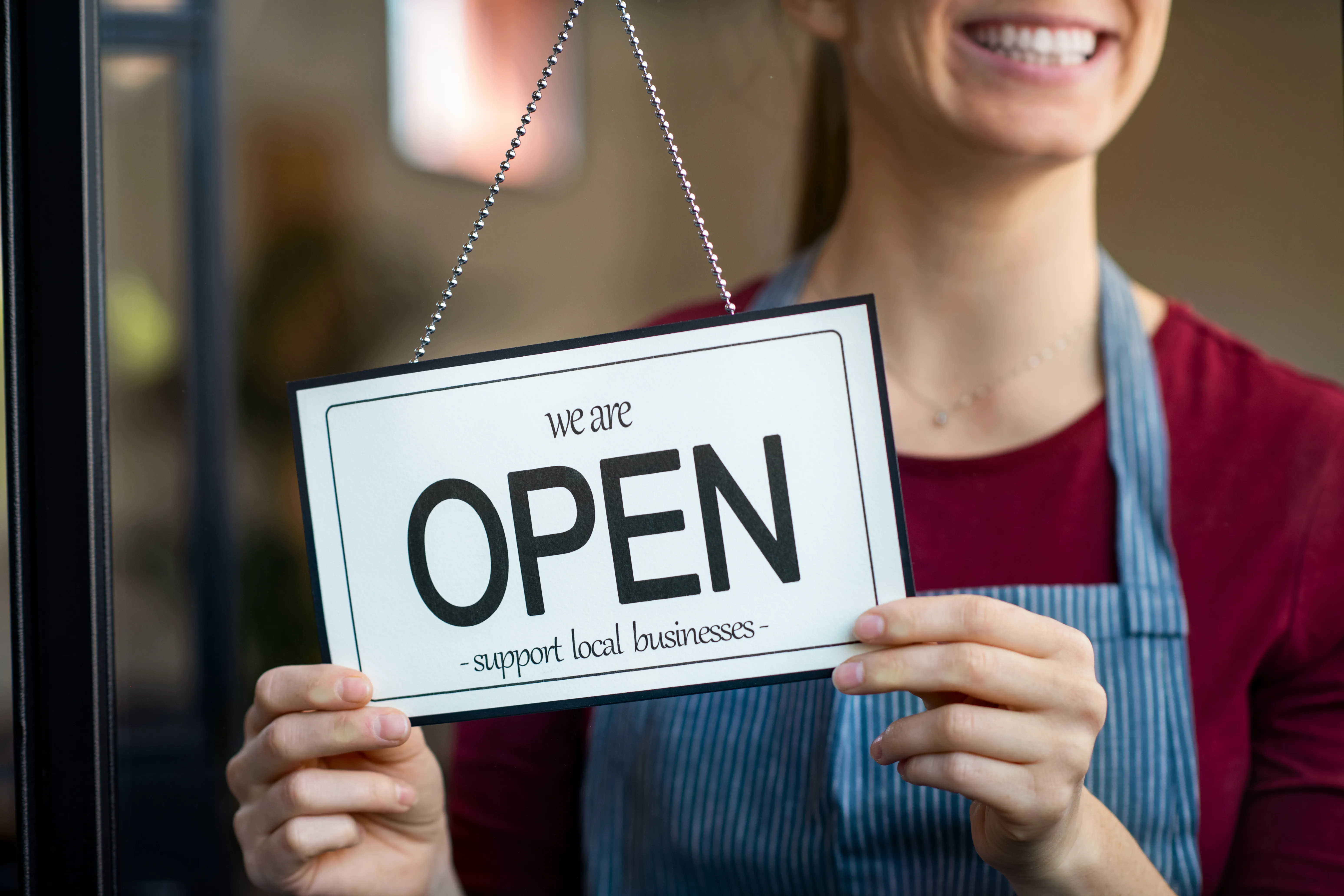 Woman holding up a shop open sign