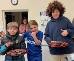 Three children in a line with two of them holding a plate of cookies